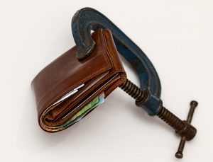 credit taxation concept of wallet squeezed with winding wrench